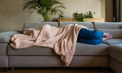Young woman sleeping under blanket<br>Young woman lying down on sofa in living room covered by blanket. Unrecognizable person.