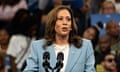 a woman in a suit speaks to a crowd of people