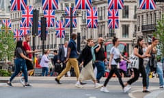 Shoppers on Oxford Street in central London cross a road under lots of suspended union flags