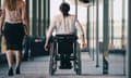 Female entrepreneur walking with disabled businesswoman in corridor at workplace