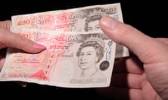 A woman hands two £50 pound notes to a man