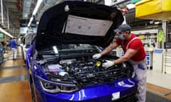 A worker inspects under the hood of a Volkswagen Golf 8.