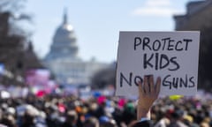 Crowd in front of The White House in Washington DC. In the foreground is a sign saying protect kids, not guns