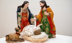 Painted porcelain figures wearing red and green robes, one female and one male, in front of a baby doll and a dog.