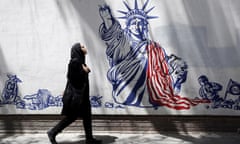 An Iranian woman walks past an anti-US mural in Tehran