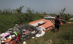 A woman walks past some furniture and other belongings she could salvage