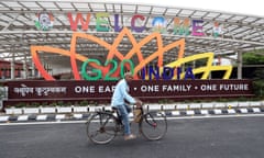 A man rides his bicycle past the venue of the G20 summit in Delhi which displays the message, One Earth, One Family, One Future.