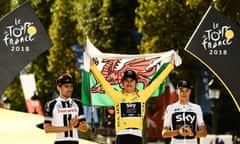 Geraint Thomas holds a Welsh flag high on the podium alongside second-placed Tom Dumoulin and third-placed Chris Froome.