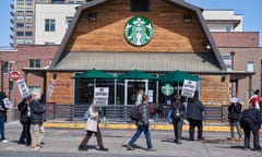 People with signs walking in front of a Starbucks store