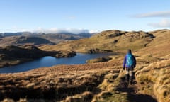 Hiker with rucksack walking next to Angle Tarn