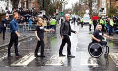 Prince Harry and Jon Bon Jovi cross the road outside Abbey Road Studios in rainy London