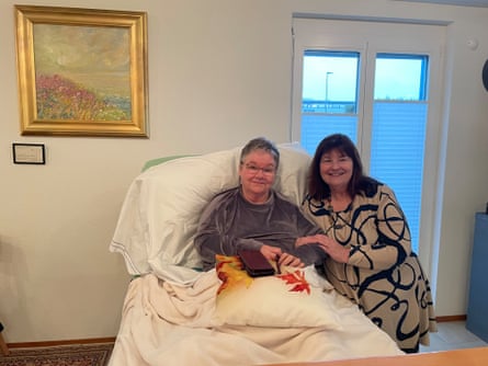 Sharon Johnston sat up in a bed, with Sue Lawford holding on to her arm, both smiling at the camera.