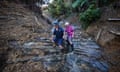 Karyn Maddren (L) and Sue Meszaros (R) walk down a layered rock waterfall unearthed by a huge landslide on their sheep farm.