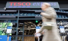 A pedestrian walks past a Tesco Express store