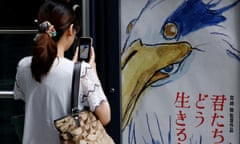 A woman takes a picture of a movie poster for Hayao Miyazaki's film How Do You Live? outside a movie theatre in Tokyo, Japan, on Friday