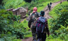 Two March 23 Movement (M23) rebels walk towards an M23 rebel-held position on Kavumu hill in North Kivu, eastern Democratic Republic of the Congo (DRC)