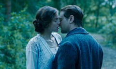 Emma Corrin as Lady Chatterley and Jack O'Connell as Mellors on the brink of kissing, outdoors.