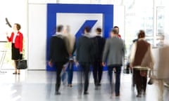 People walk past a Deutsche Bank logo