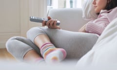 Woman lying on sofa, watching television