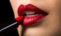 a close-up of a woman applying red lipstick