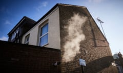 Smoke ascends the side of a British house from a condensing boiler outlet.