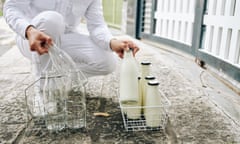 Milkman wearing perfect white outfit delivering fresh milk and taking empty bottles back in early morning.