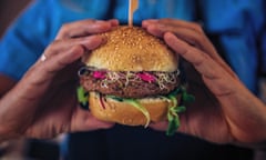 Someone holds a veggie burger in a bun