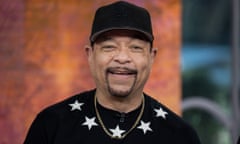 Ice-T, smiling, in a baseball hat and black jumper with white stars around the collar