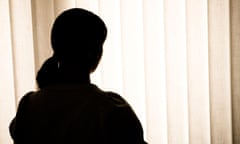 Anonymous woman silhouetted against window blinds