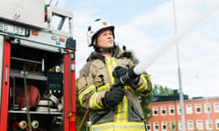 Female firefighter using fire hose next to truck