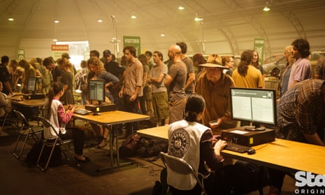 People queue in a dusty, polluted hangar