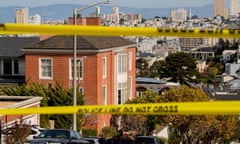 Taken from the top of a hill, with the hills of Oakland far in the distance, a three-story brick house on a corner, with yellow police tape in the blurred foreground.