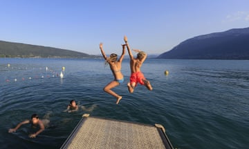Children jump off the pontoon into the lake.