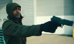 Kane ‘Kano’ Robinson as Sully in Top Boy, hood up, pointing a gun