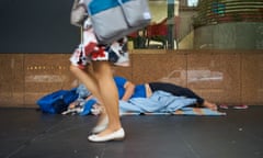 A homeless person sleeping on the street<br>Melbourne, Australia - 4 Nov 2018: A homeless person is sleeping on the street during the day and a pedestrian is walking in front of him/her.