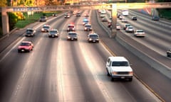 A white SUV drives down a large freeway followed by police cars.