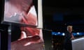 a man with a bandage on his ear talks to an audience in front of an image of himself taking cover from a gunman