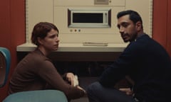 Jessie Buckley and Riz Ahmed sit by a strange microwave-like device in Fingernails.