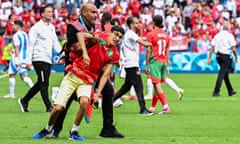 Security staff remove fans from the pitch in the match between Morocco and Argentina.