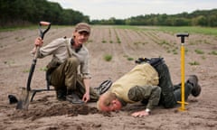 Mackenzie Crook and Toby Jones, who has his face right down in a hole in a muddy field