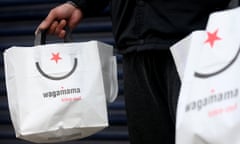 A Deliveroo worker collects an order from a Wagamama restaurant’s deliveries entrance