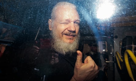 Assange does a thumbs-up gesture through a vehicle window
