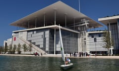 A man sails in front of the newly built Athens national Opera and library buildings at the Stavros Niarchos Cultural Center in Athens, Greece.