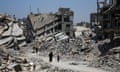 Palestinians walk past the rubble of buildings destroyed during the Israeli military offensive in Khan Younis, southern Gaza in July 2024