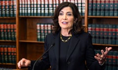 White woman in black suit sits in front of shelves full of law books