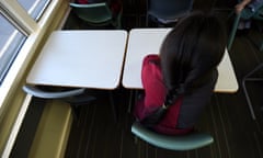 A girl sitting at a desk with an empty space next to her.