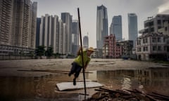 A worker does an impromptu pole-vault to leap across a puddle while working 
on electric cabling on the fringes of an old 'urban village' which has become surrounded by new skyscrapers in Guangzhou, China's southern metropolis