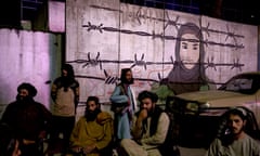 Taliban members in front of a mural depicting a woman behind barbed wire in Kabul, Afghanistan