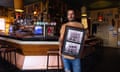 The publican of the Grace Emily hotel, Symon Jarowyj, holds up archival images of the Adelaide venue