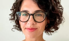 Young-ish white woman with curly brown hair and tortoiseshell glasses wearing white blouse.